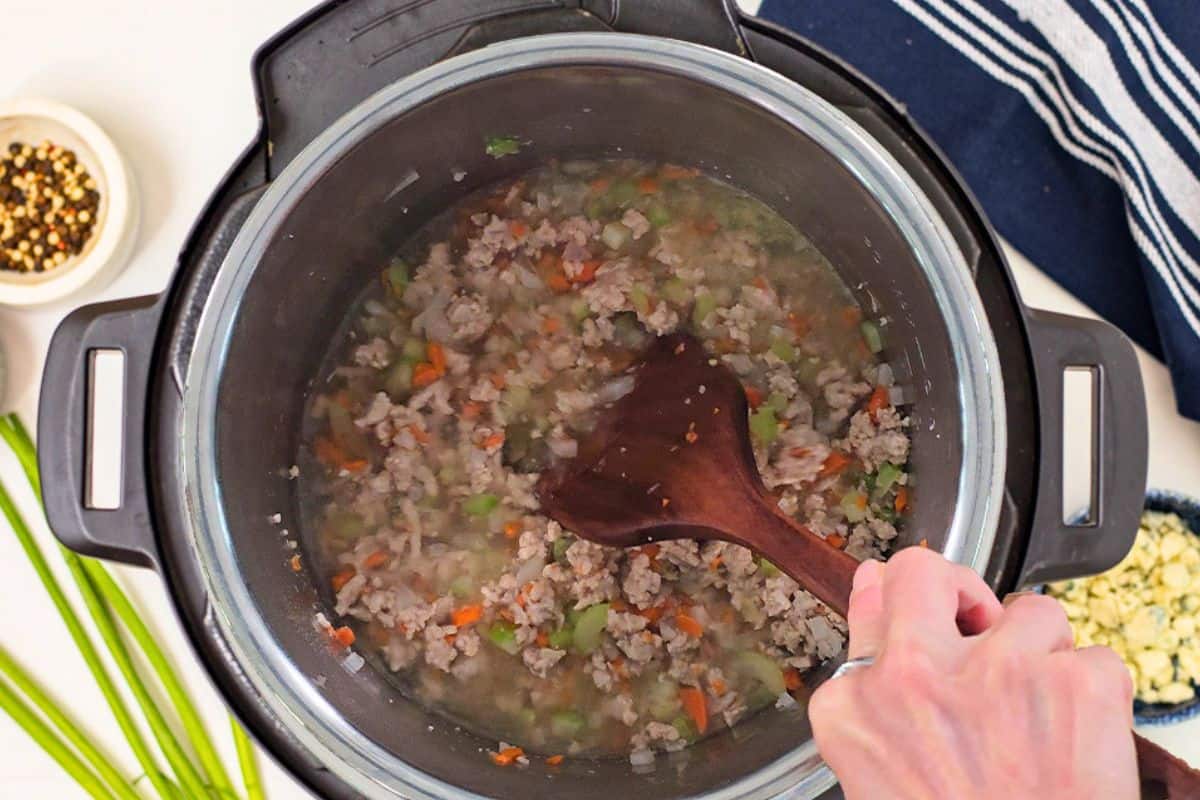 Buffalo Chicken Chili with Fire Roasted Tomatoes Wooden spatula scraping bottom of inner pot after adding in chicken stock.