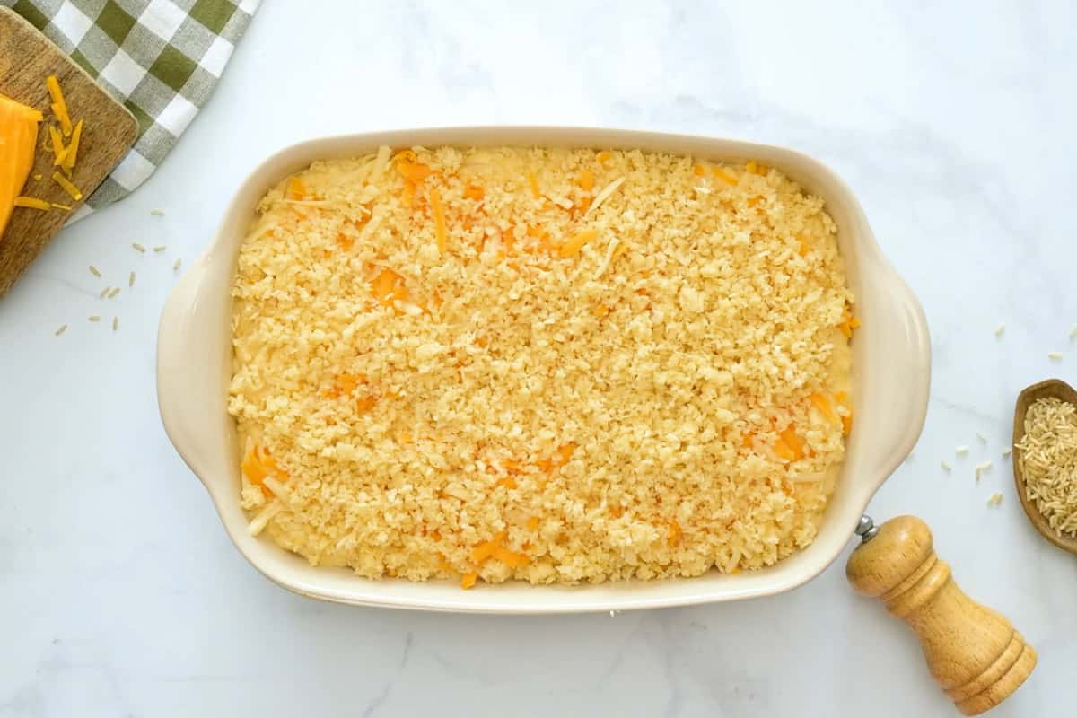 Mac and Cheese Baked Macaroni coated in creamy, cheese sauce in baking dish topped with more shredded cheese and panko parmesan breadcrumb.