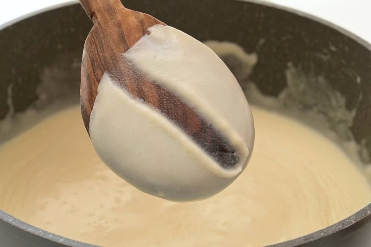 Holiday Mac and Cheese Recipe A line drawn down a wooden spoon showing that the cream sauce has thickened.