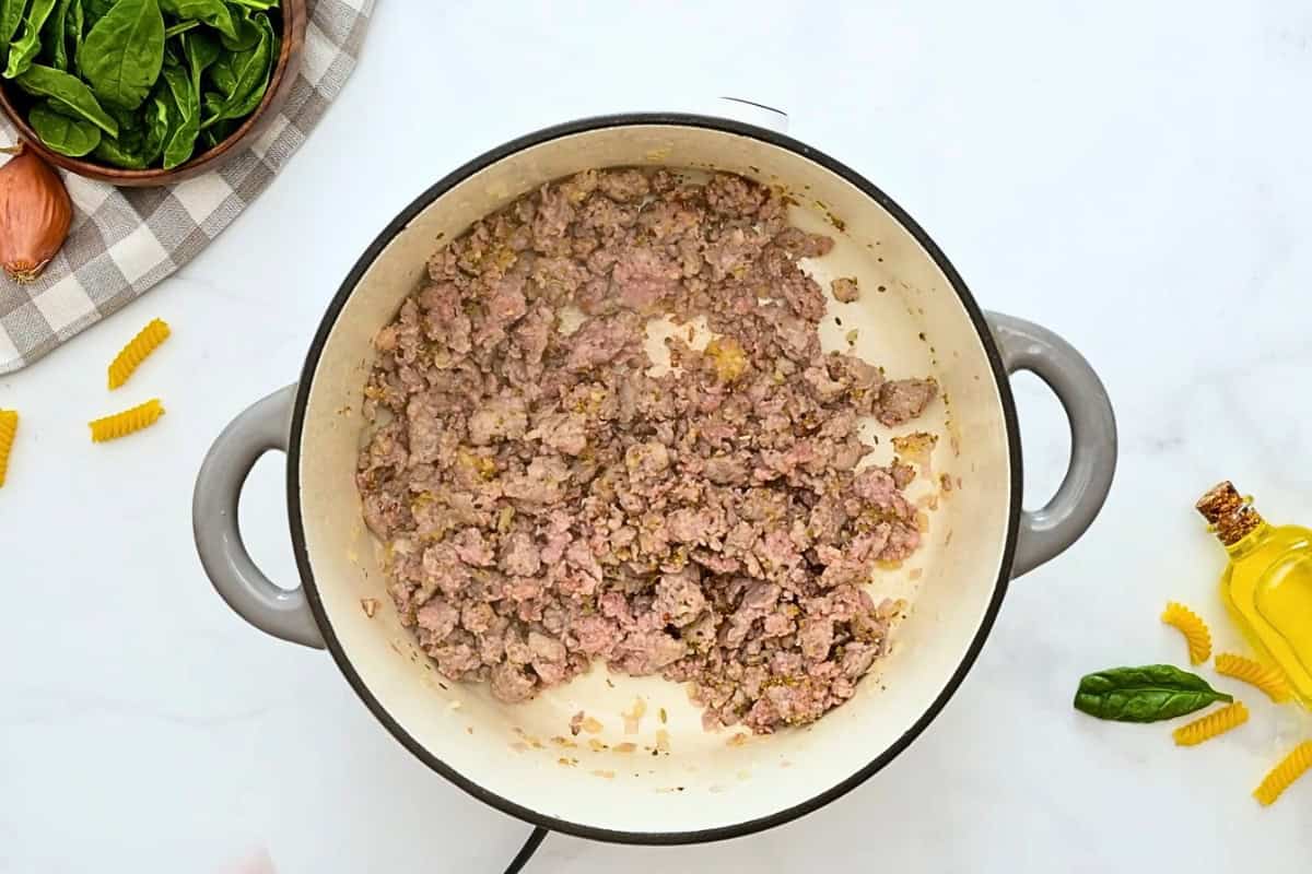 Italian sausage browned with minced shallots and garlic in large stockpot.