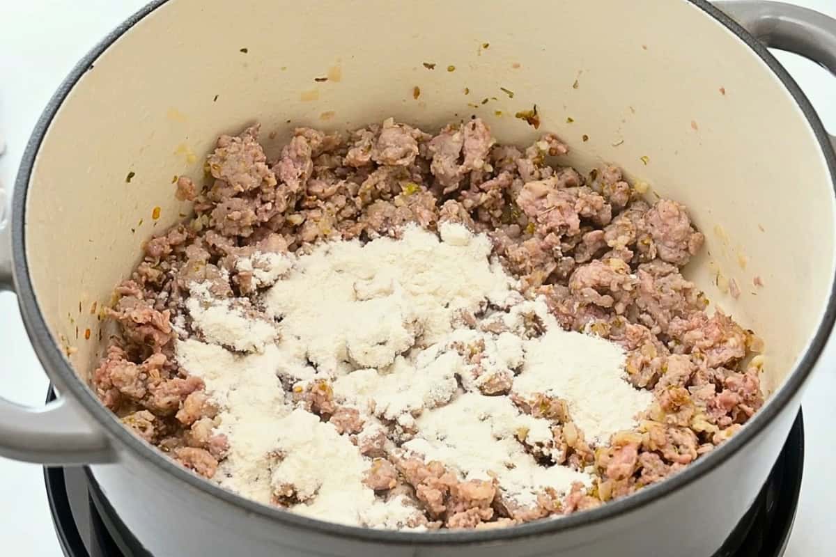 Flour sprinkled over browned sausage in large stockpot.