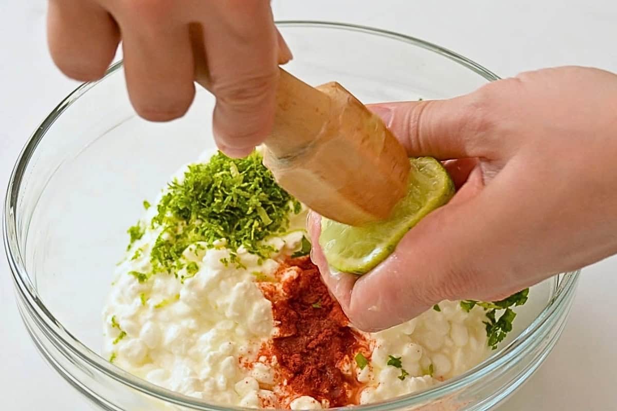 Ground Beef Sweet Potato Bowls with Cottage Cheese Lime being juiced into a bowl of cottage cheese with cilantro, lime zest, and smoked paprika.